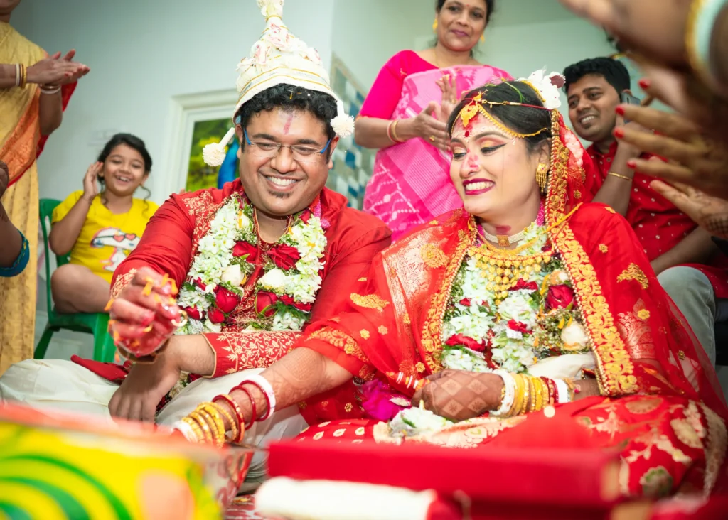 Candid moment of Bengali bride and groom laughing during wedding ritual photographed in Kolkata
